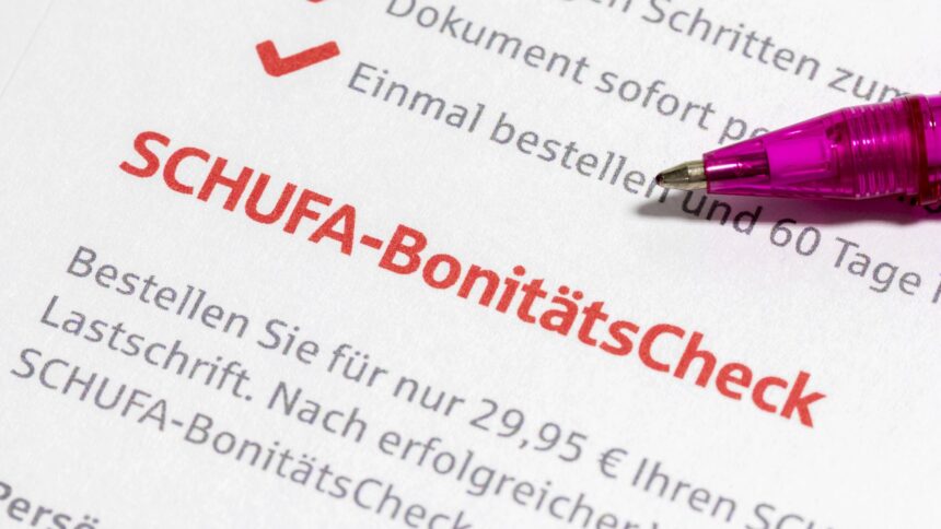 Ein Pinker Kugelschreiber zeigt auf auf einen großen, roten Schriftzug der sich "SCHUFA-BonitätsCheck" ließt.