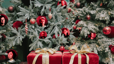 Eine Weihnachtsszene mit roten Geschenken und Kugeln am Baum, in die Kugeln sind Gesichter der Teammitglieder fotomontiert.