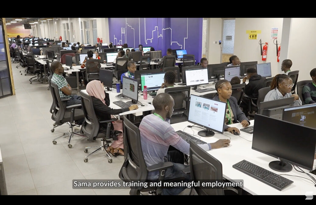 Der Screenshot zeigt ein volles Büro mit vielen Angestellten an Computerbildschirmen.