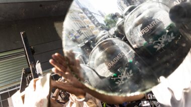 Demonstrierende in Buenos Aires, in einem Spiegel spiegeln sich Polizist*innen