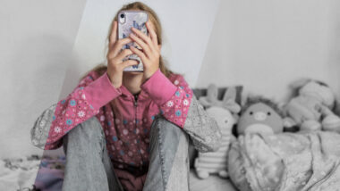 Teenagerin mit Handy vor dem Gesicht