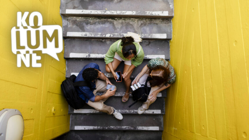 Drei Jugendliche sitzen mit ihren Smartphones auf einer Treppe, von oben fotografiert.