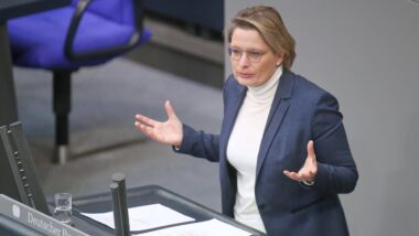 Person im hellen Rollkragen und blauem Blazer steht am Rednerpult im Bundestag