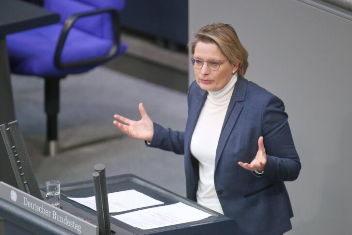 Person im hellen Rollkragen und blauem Blazer steht am Rednerpult im Bundestag