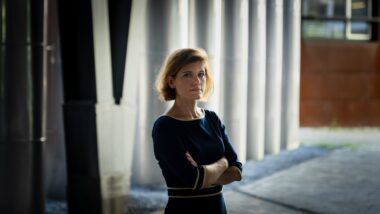 Mensch steht mit gekreuzten Armen vor einer Wand