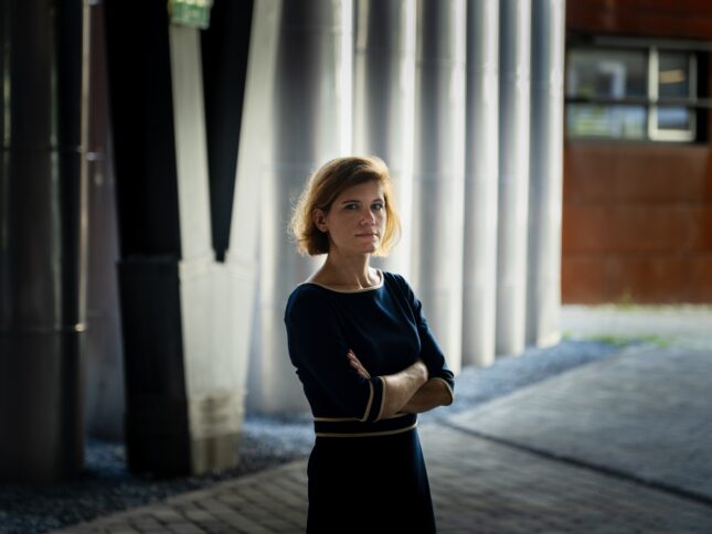 Mensch steht mit gekreuzten Armen vor einer Wand