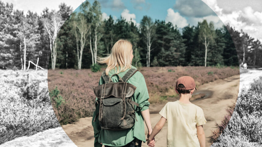Eine Frau und ein Kind gehen Hand in Hand einen Feldweg entlang.