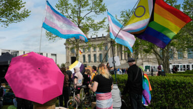 Eine Menschenmenge vor dem Bundestag mit trans und Regenbogenflaggen.
