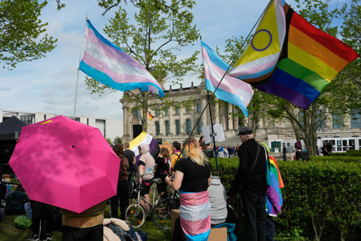 Eine Menschenmenge vor dem Bundestag mit trans und Regenbogenflaggen.