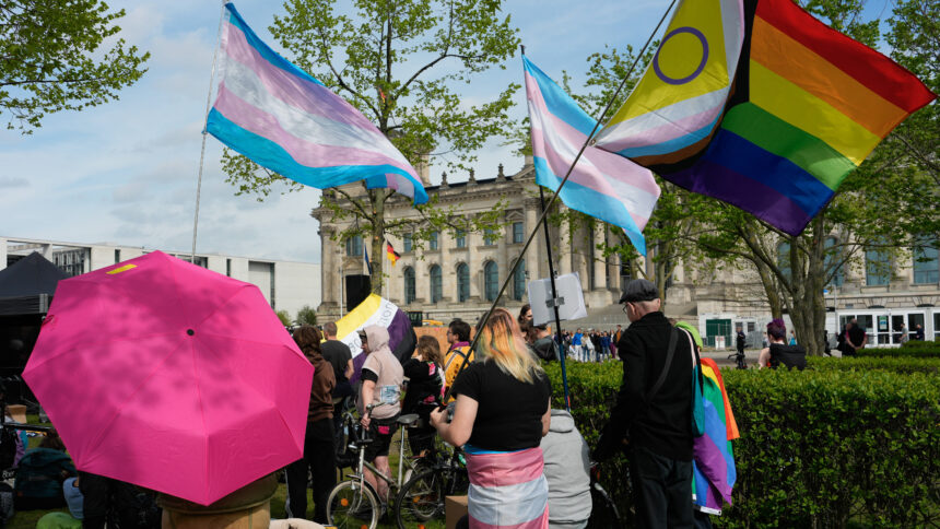 Eine Menschenmenge vor dem Bundestag mit trans und Regenbogenflaggen.