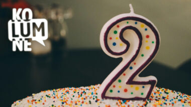 Ein bunter Kuchen auf dem eine Kerze in Form der Ziffer "2" steht.