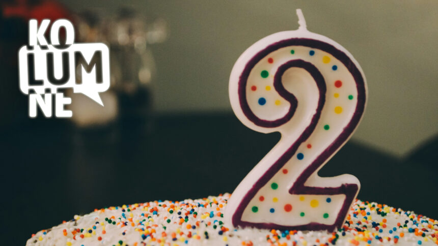 Ein bunter Kuchen auf dem eine Kerze in Form der Ziffer "2" steht.