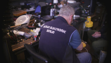 Muharrem Batman sitzt vor seinem Werkstatttisch und repariert eine Lampe.