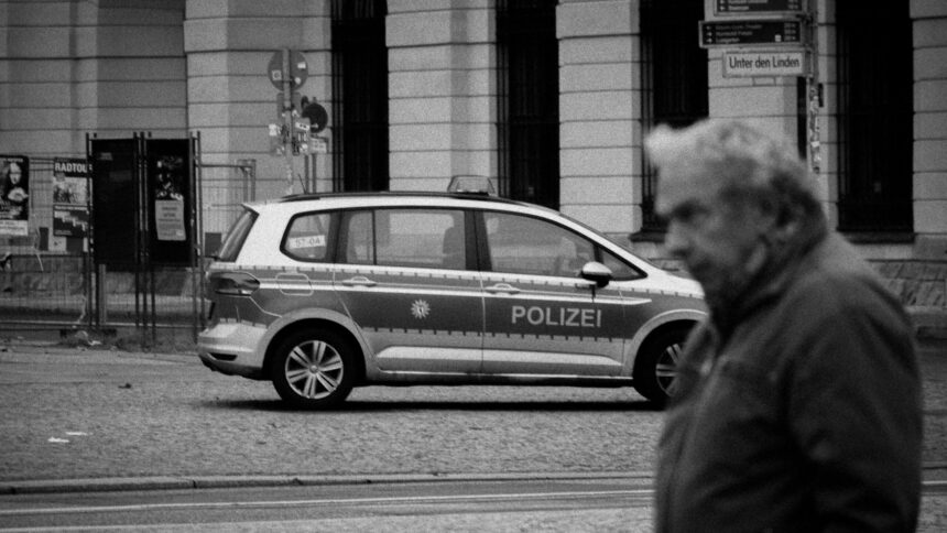 Graustufenbild eines Polizeiautos, das in der Straße "Unter den Linden" steht