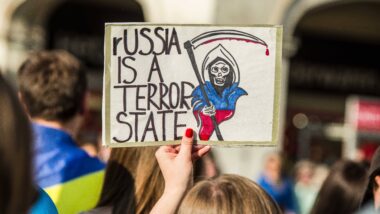 Jemand hält ein Plakat mit der Aufschrift hoch: "Russia is a terrorist state"