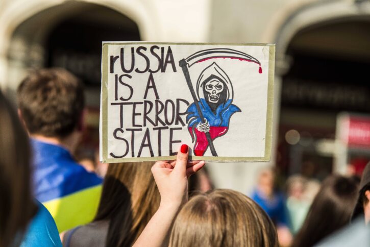 Jemand hält ein Plakat mit der Aufschrift hoch: "Russia is a terrorist state"