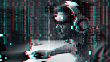 Ein Mann mit einem Headset spielt Online – oder überwacht Online-Spieler:innen, je nach Blickwinkel.