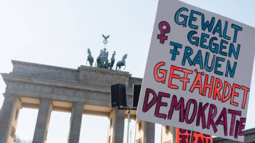 Demo-Schild vor dem Brandenburger-Tor, Aufschrift: Gewalt gegen. Frauen gefährdet Demokratie
