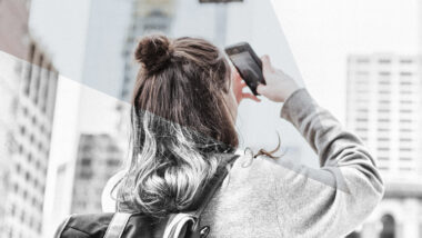 Eine Teenagerin fotografiert mit dem Smartphone Hochhäuser