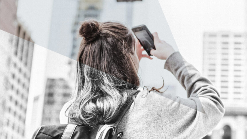 Eine Teenagerin fotografiert mit dem Smartphone Hochhäuser