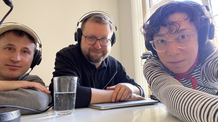 Drei Personen mit Kopfhörer machen Selfie am Tisch