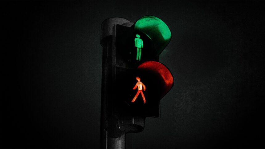 Fußgängerampel, bei der rot und grün gleichzeitig leuchten; das stehende Männchen leuchtet grün, das gehende rot