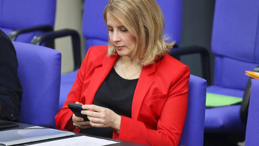 Frau mit rotem Jacket schaut auf ihr Handy.