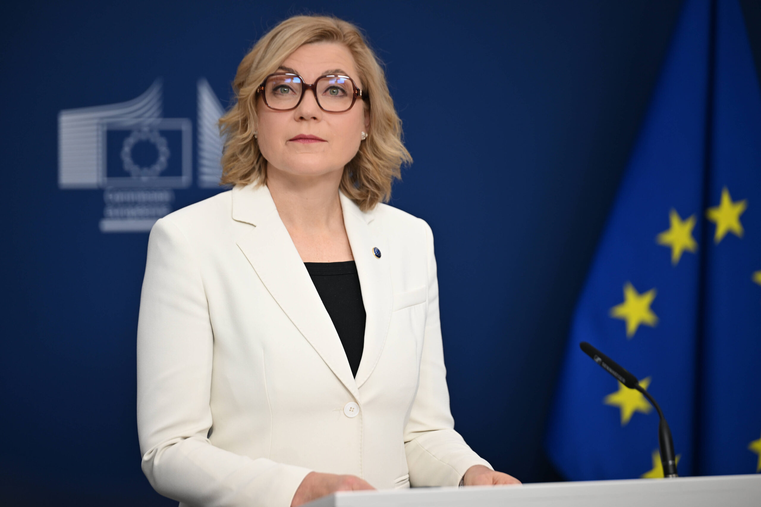 Frau mit Brille in weißem Blazer an Pult