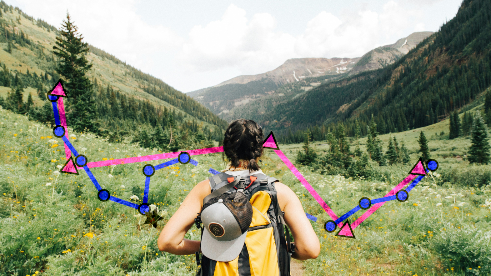 Frau mit Rucksack von hinten fotografiert wandert durch ein grünes Tal.