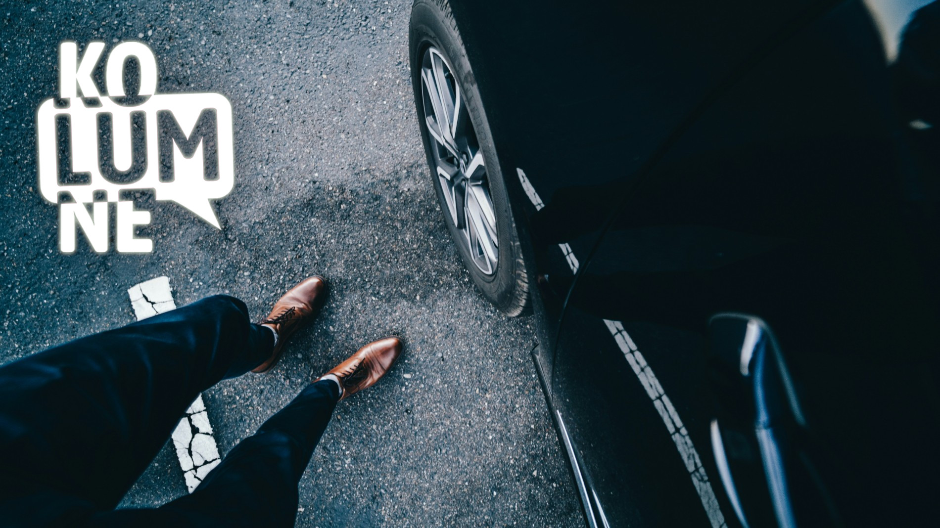 Ein Paar Beine mit braunen Lederschuhen steht vor einem schwarzen Auto
