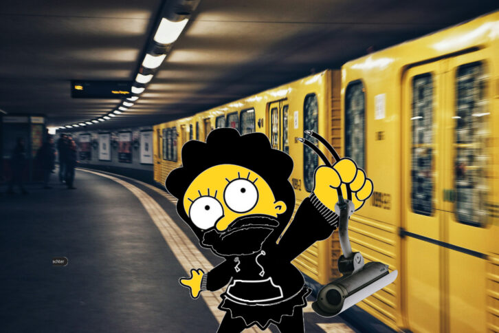 Eine gelbe Figur hält eine abgetrennte Kamera, im Hintergrund fährt eine Berliner U-Bahn.