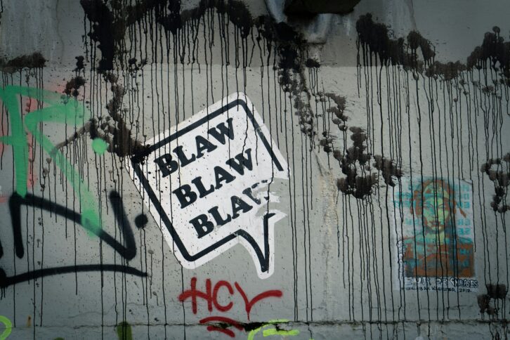 Sprachblase mit dem Inhalt "Blaw Blaw Blaw" als Straßenkunst-Motiv auf einer gefärbten Wand.