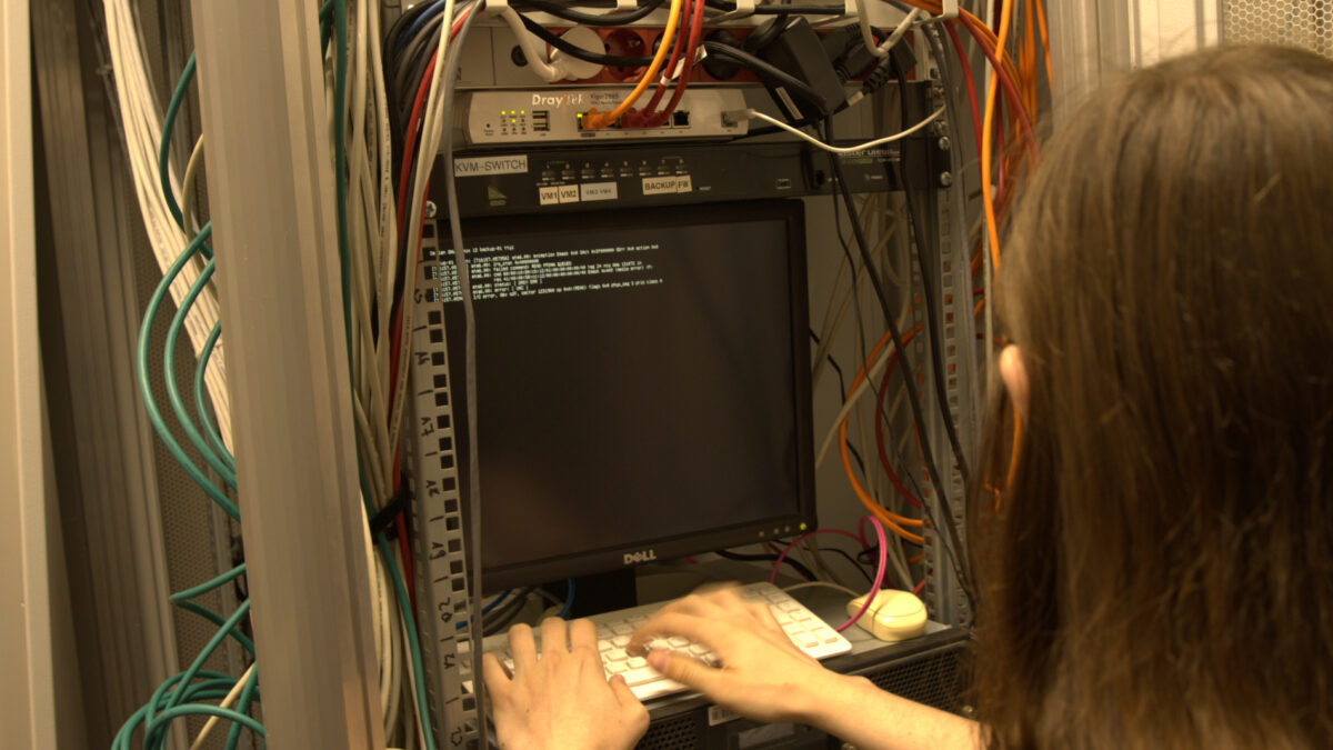 Eine Person bedient einen Computer, der Bildschirm zeigt ein Terminal.