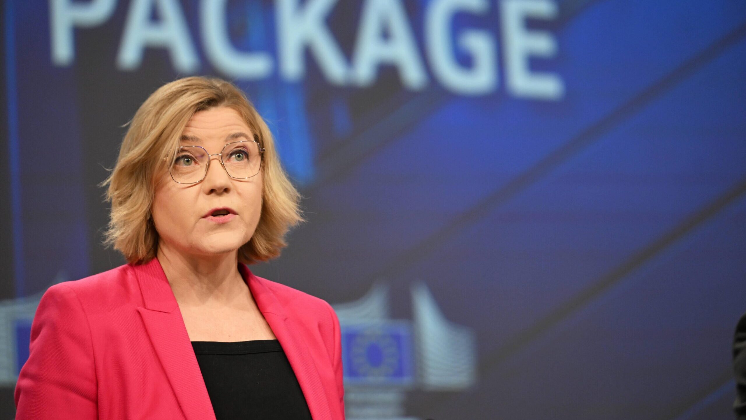 EU-Kommissarin Henna Virkkunen steht auf einer Bühne, im Hintergrund auf der Leinwand steht das Wort "package"