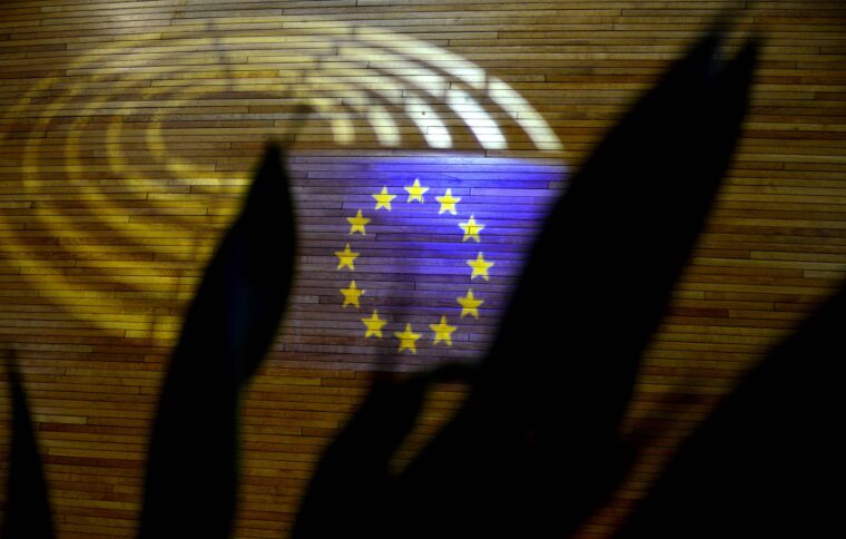 Die blaue Flagge der EU zwischen Licht und Schatten auf einer Wand im Parlamentsgebäude in Straßburg.