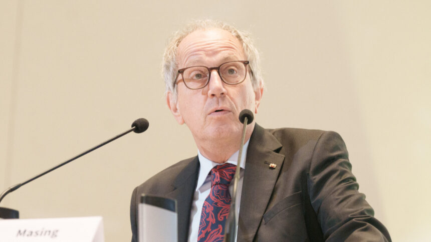 Man mit Brille und Anzug spricht in Mikrofone
