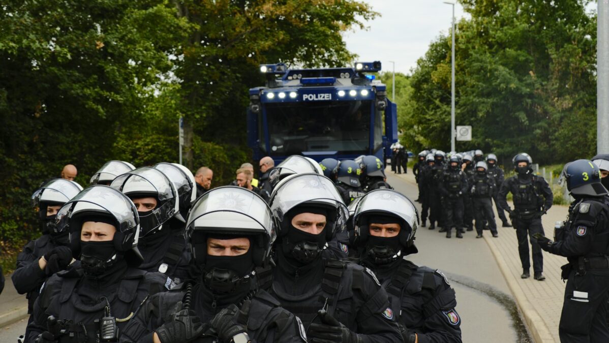 Polizei mit Helmen vor Wasserwerfer.