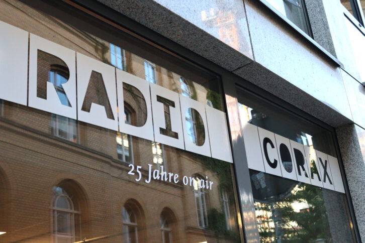 Auf einer großen Fensterscheibe steht in Großbuchstaben "Radio Corax" geschrieben.