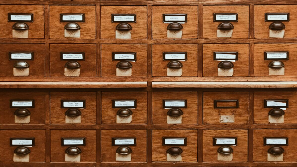 Holzschrank mit mehreren kleinen Schubladen, jede mit einem Griff und einem beschrifteten Etikett