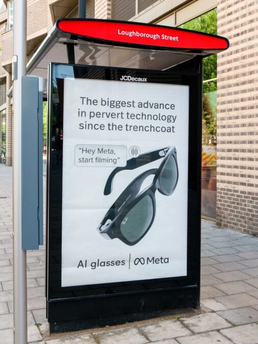 Werbeplakat an einer Bushaltestelle mit der Aufschrift 'The biggest advance in pervert technology since the trenchcoat' und einem Bild von einer Brille mit dem Text 'Hey Meta, start filming' sowie dem Schriftzug 'AI glasses | Meta'