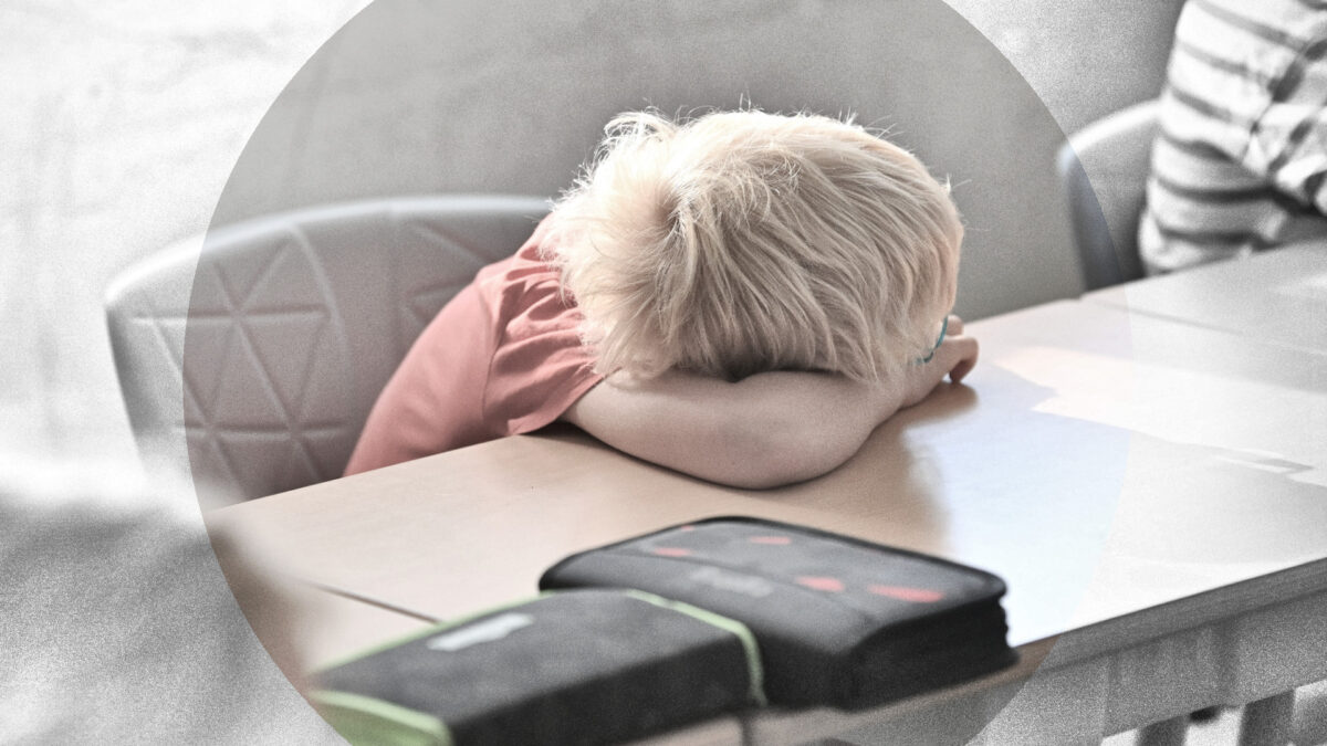 Ein Grundschüler lässt seinen Kopf auf dem Tisch ruhen; das Gesicht ist nicht zu sehen.