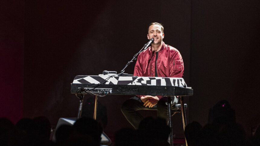 Eine Person mit roter Jacke sitzt am E-Piano