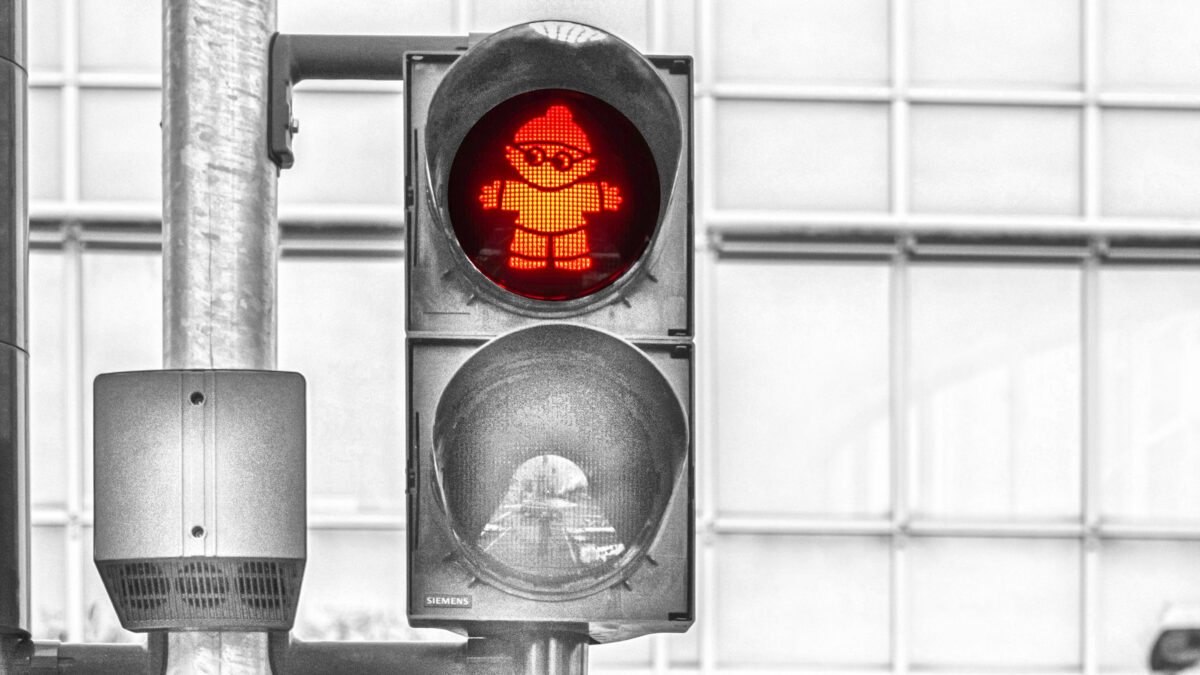 Eine Mainzelmännchen-Ampel, alles außer dem roten Signal ist ausgegraut