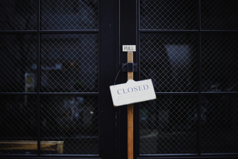 Dunkle, schwarzr Gittertüen, an denen ein Schild mit der Aufschrift "Closed" steht
