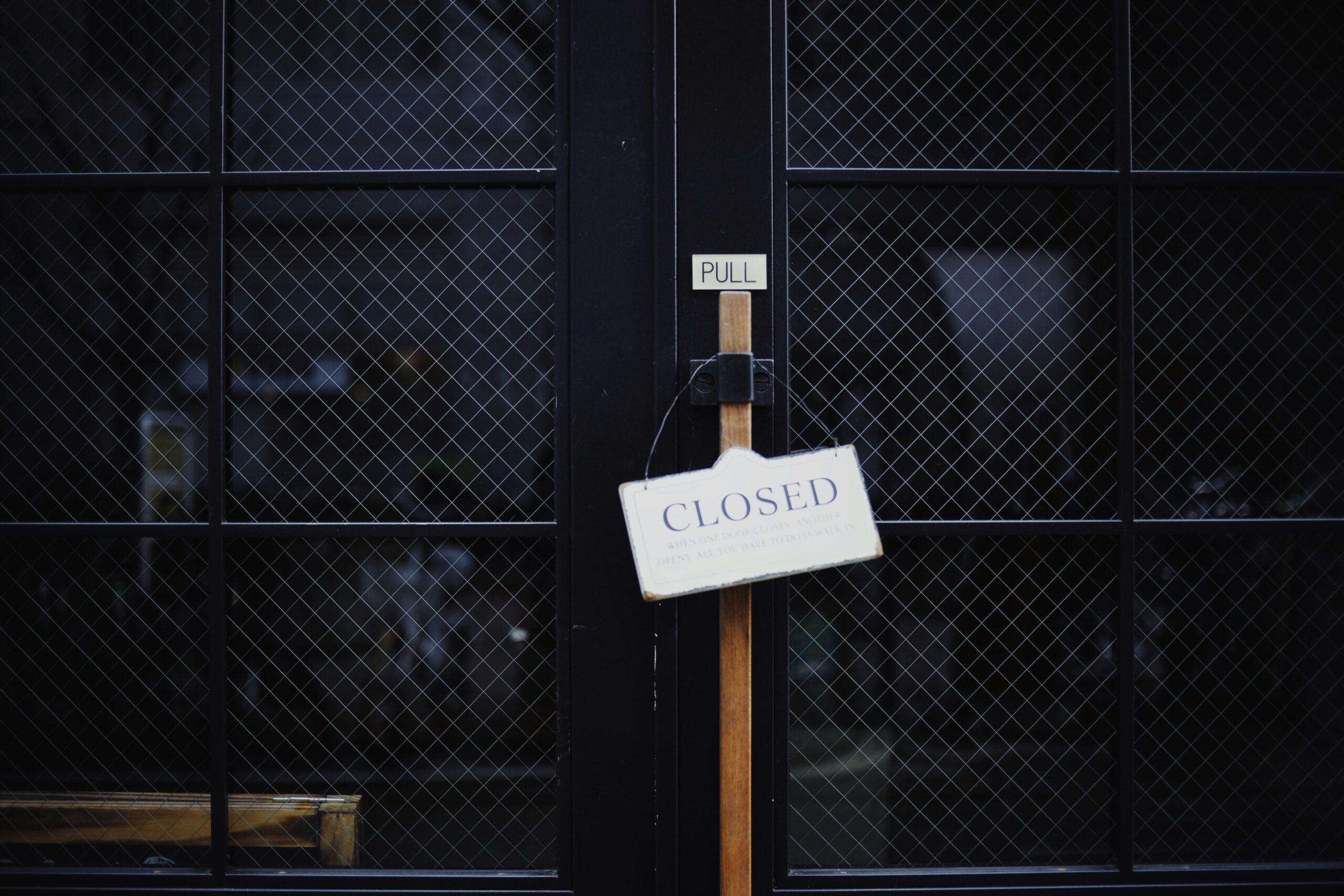 Dunkle, schwarzr Gittertüen, an denen ein Schild mit der Aufschrift "Closed" steht