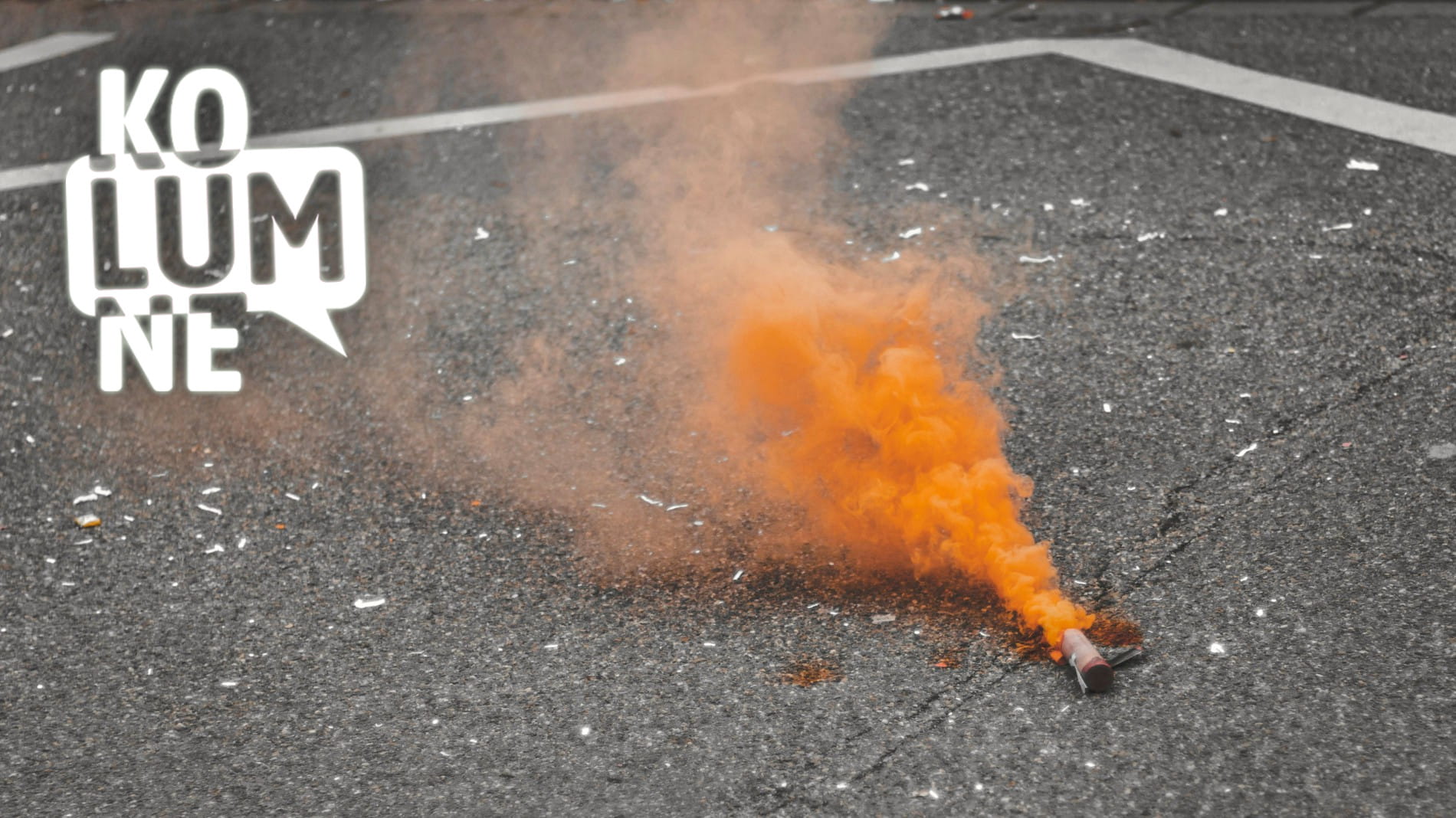 Eine Nebelkerze auf einer Straße stößt orangenen Rauch aus