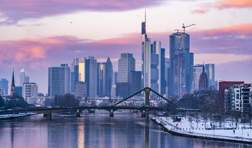 Frankfurter Skyline im rosa Morgenlicht mit Hichhäusern und Brücke