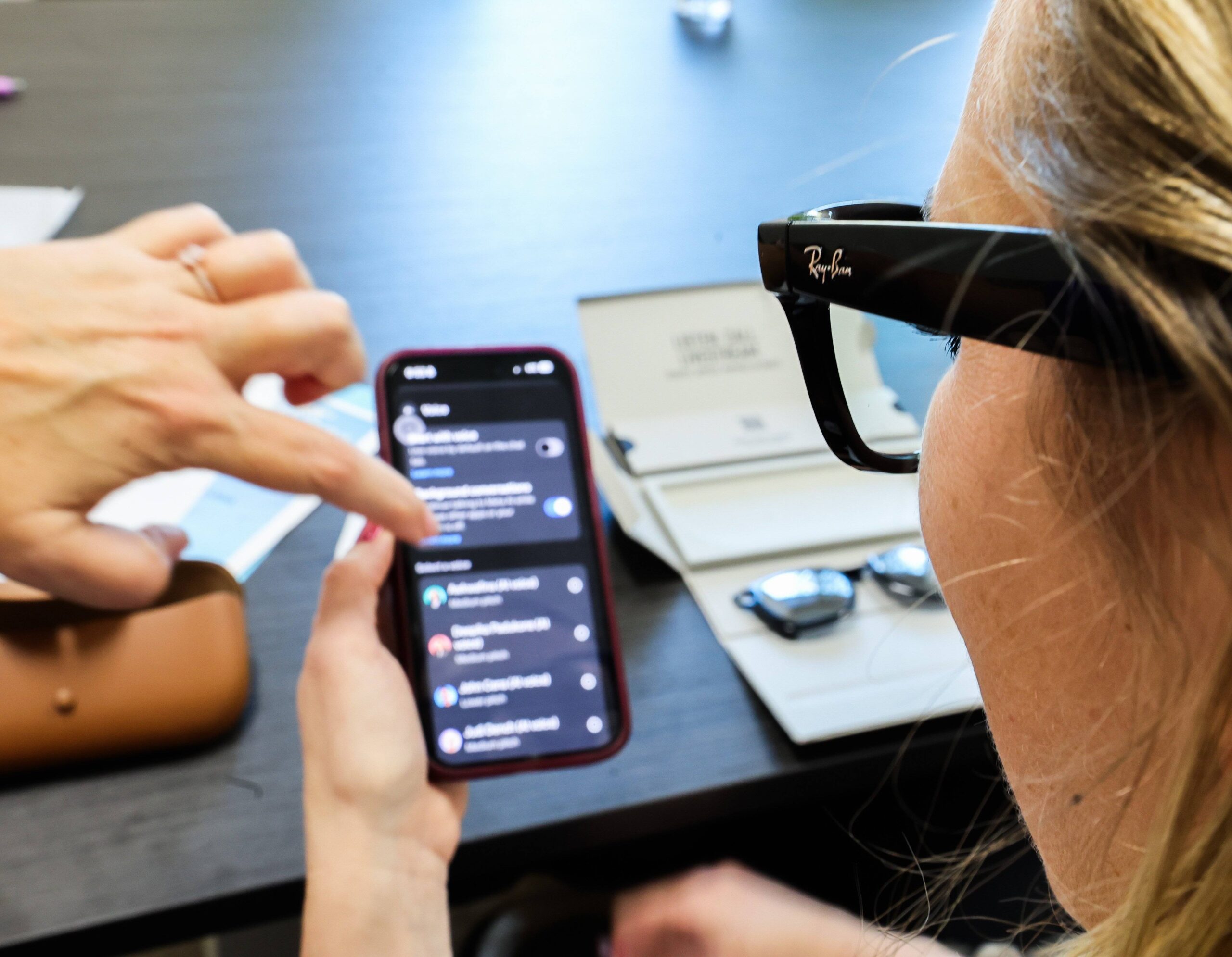 Person mit Meta-Brille schaut auf Smartphone