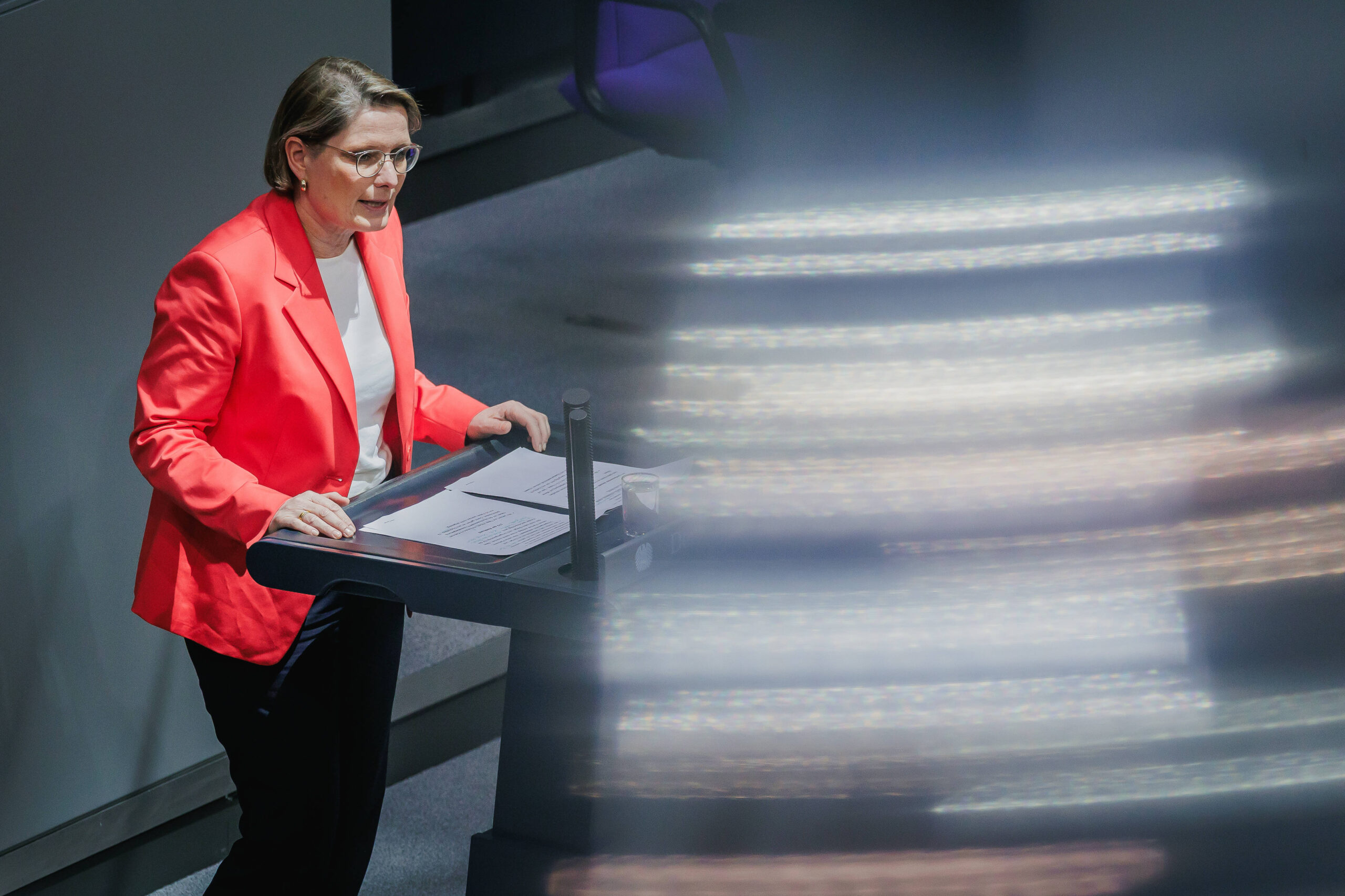 Mensch im roten Blazer am Bundestagspult