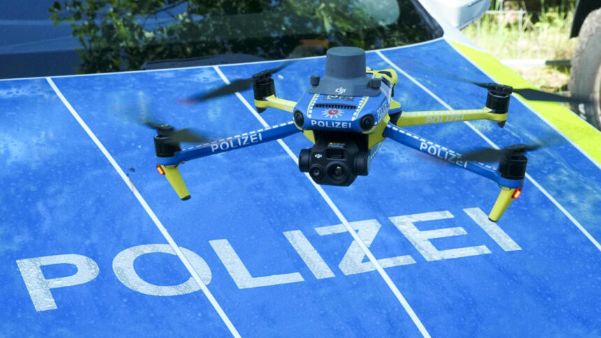 Eine Kameradrohne schwebt über der Motorhaube eines Polizeifahrzeuges.